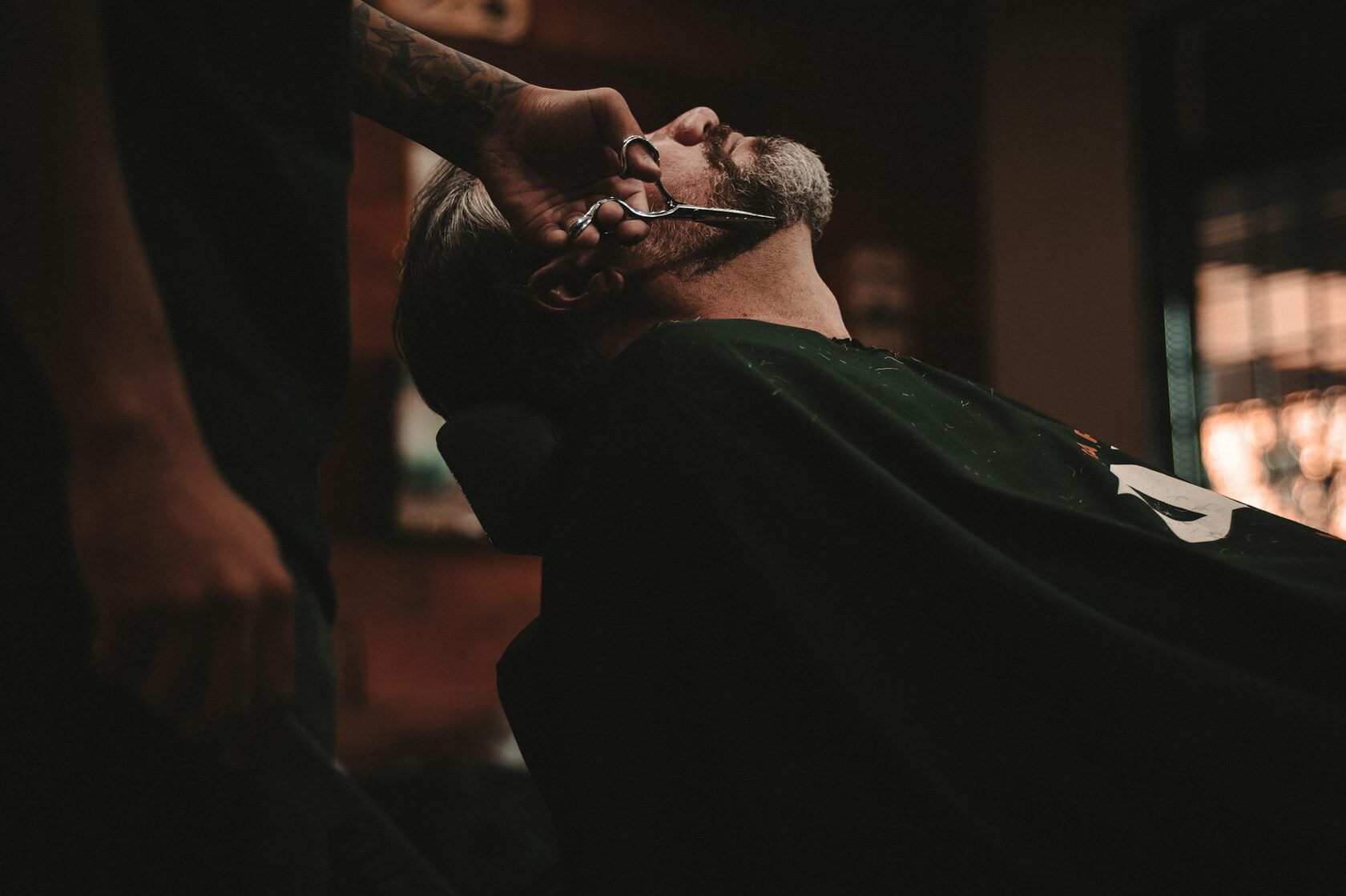 Barbeiro a fazer barba à navalha com toalha quente